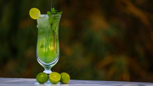 Free Tall glass of lime mint cooler with ice cubes and garnishes, served on a table. Stock Photo