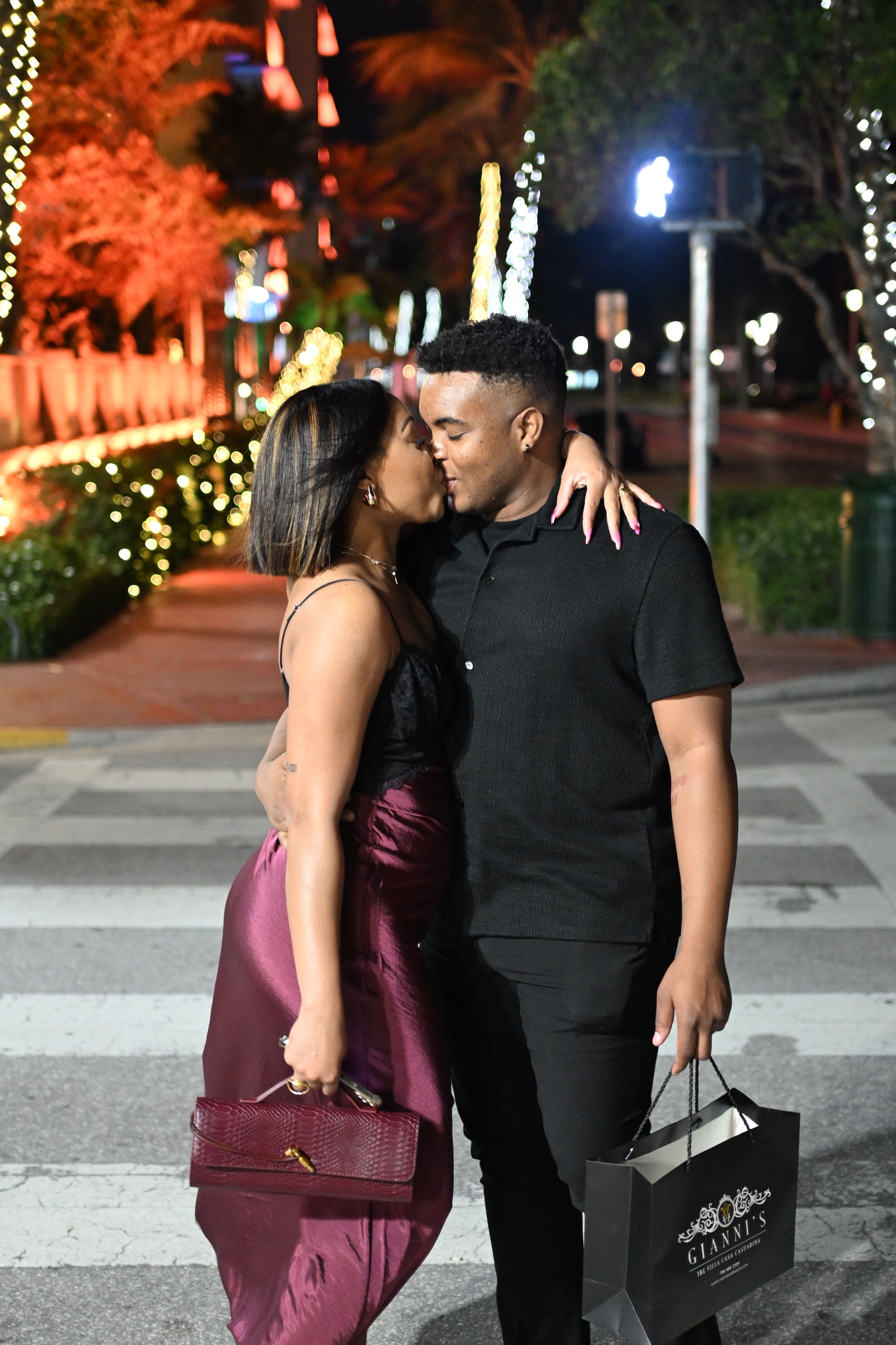 Couple sharing a tender moment on a beautifully lit city street at night.