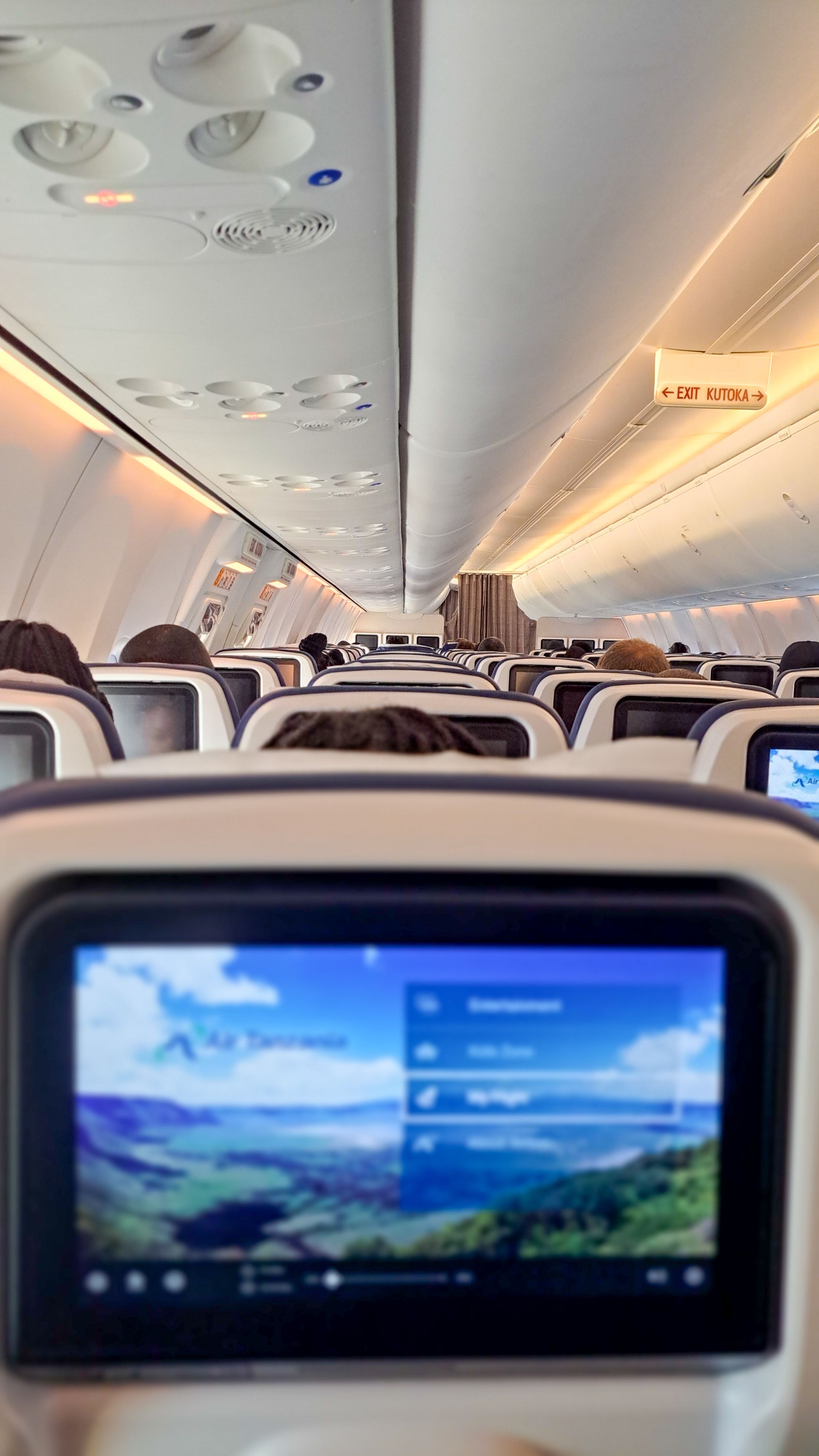 Interior view of modern airplane cabin focusing on in-flight entertainment screens.