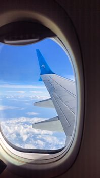 Stunning view of airplane wing against a backdrop of blue sky and clouds.
