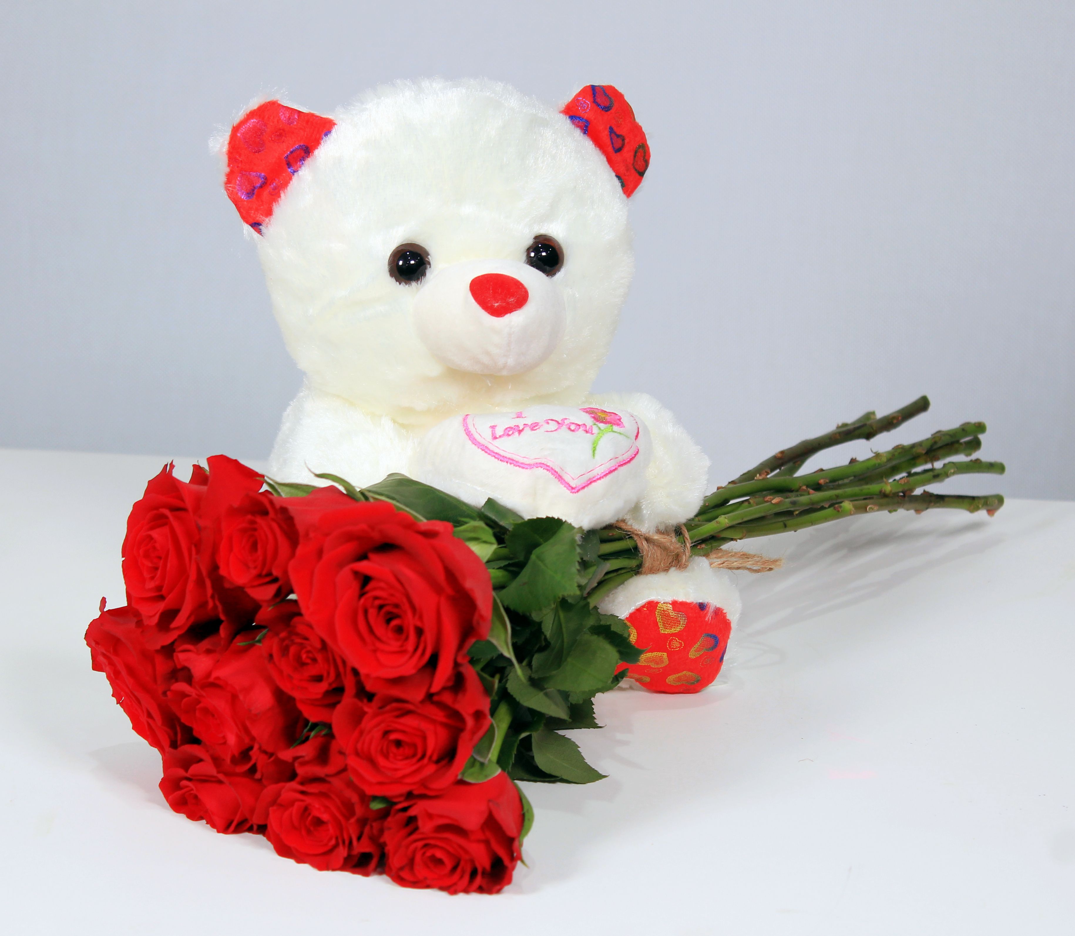 Charming teddy bear with a vibrant red rose bouquet, perfect for romantic gifts.