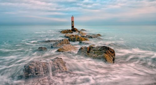 Free Tranquil ocean scene with rocks and buoy creates a calming atmosphere. Stock Photo
