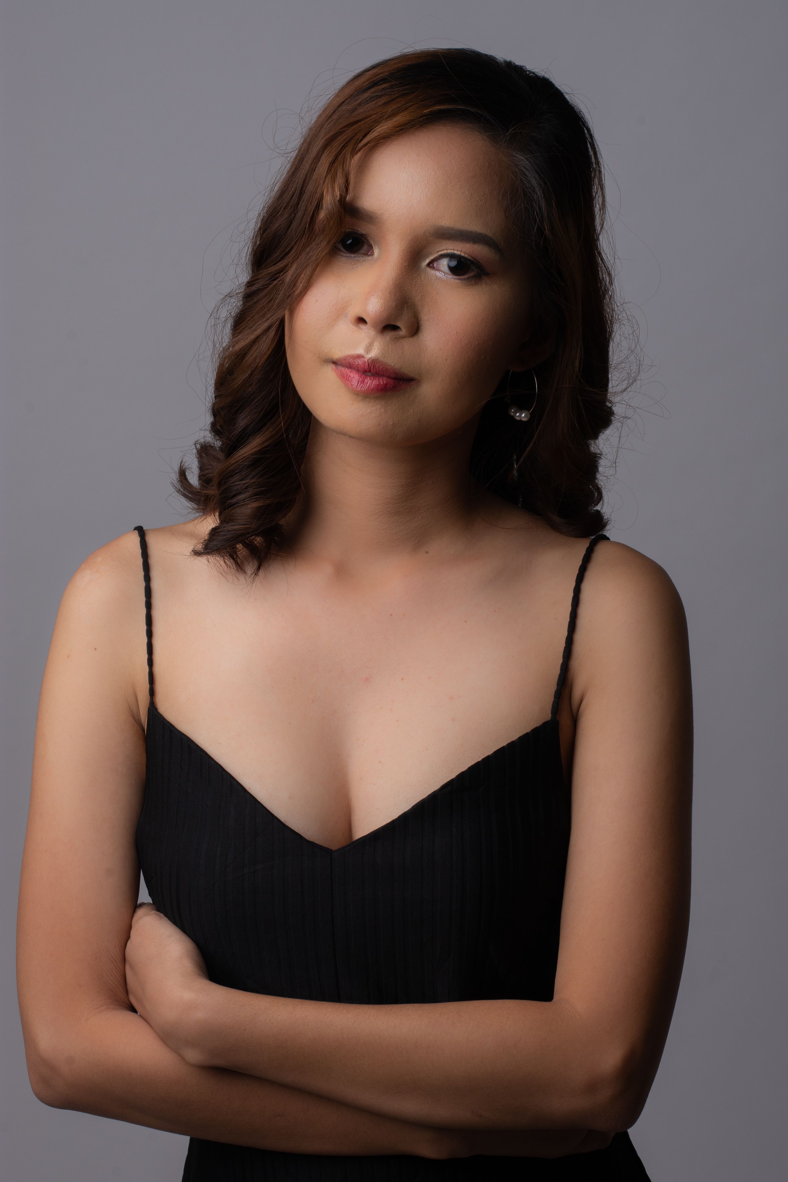 Chic portrait of a woman in a stylish black dress against a gray background.