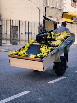 Street vendor pushes cart filled with bananas, a vibrant urban scene.