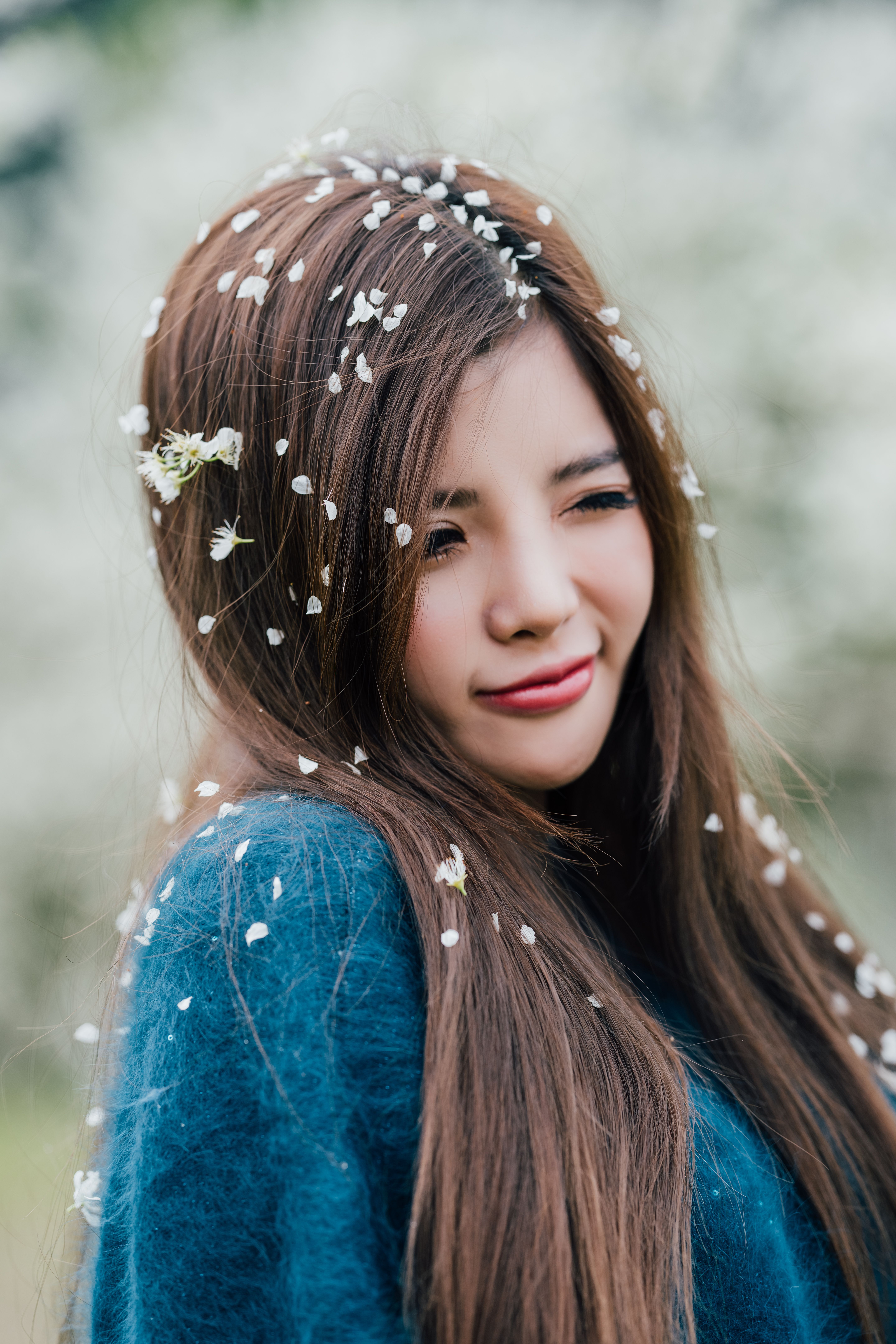 Smiling young woman with blossoms in her hair enjoying a spring day outdoors.