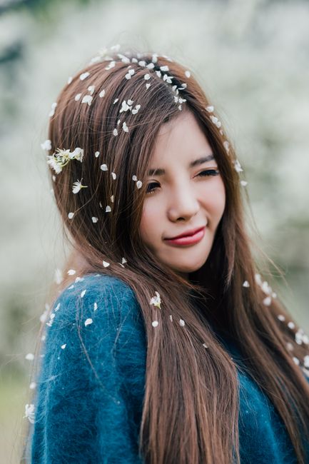 Smiling young woman with blossoms in her hair enjoying a spring day outdoors.