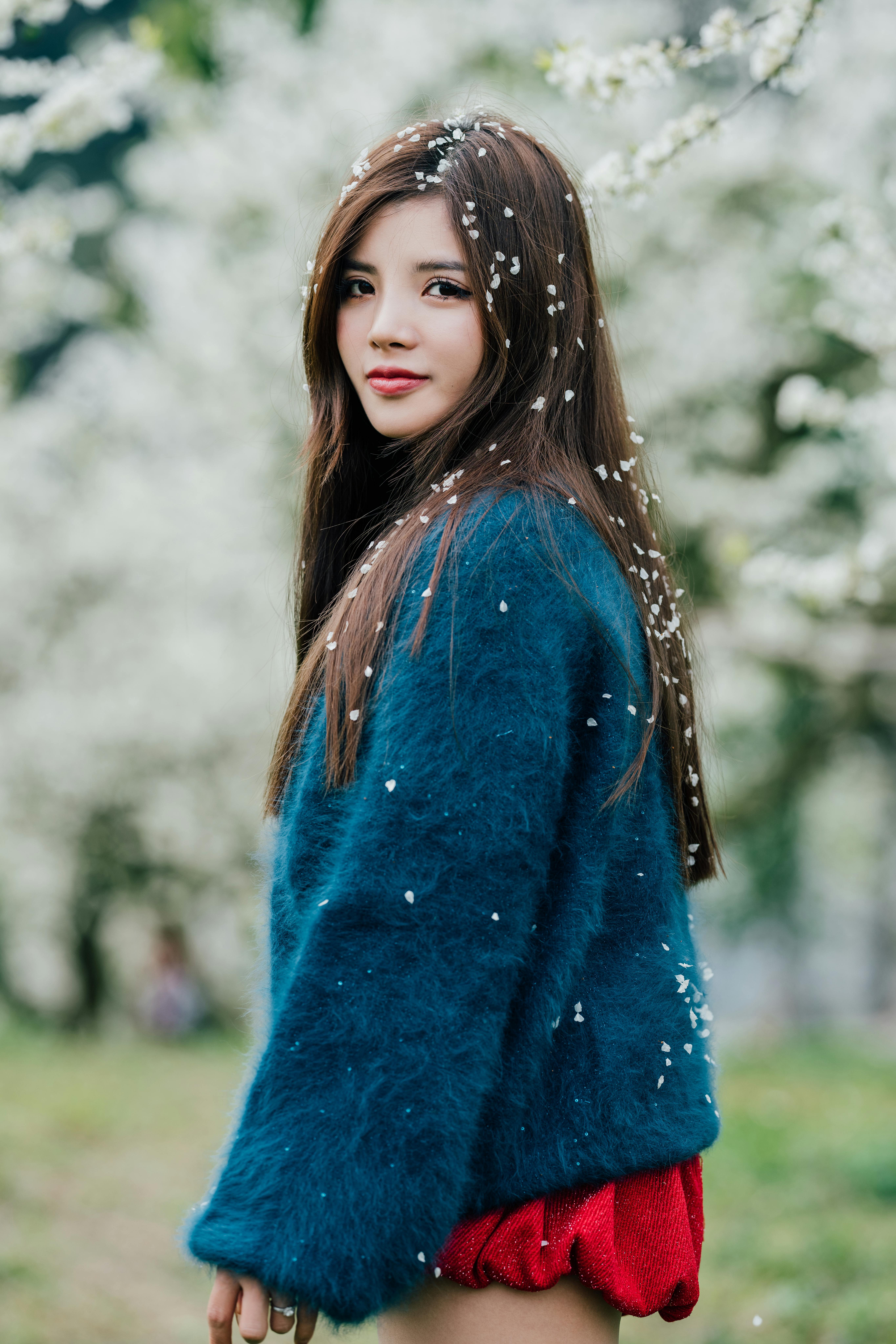 A young woman standing among spring blossoms, capturing her serene and elegant presence.