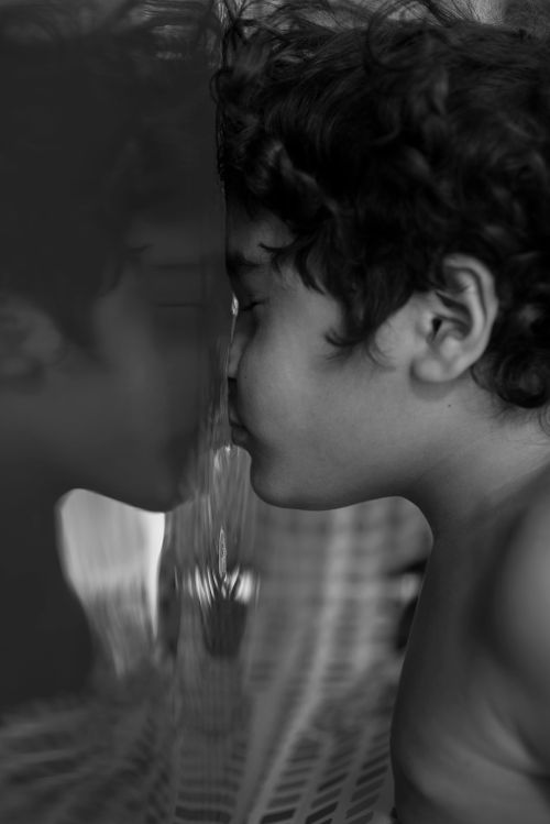 Free Black and white photo of a child looking at their reflection on a smooth surface. Stock Photo