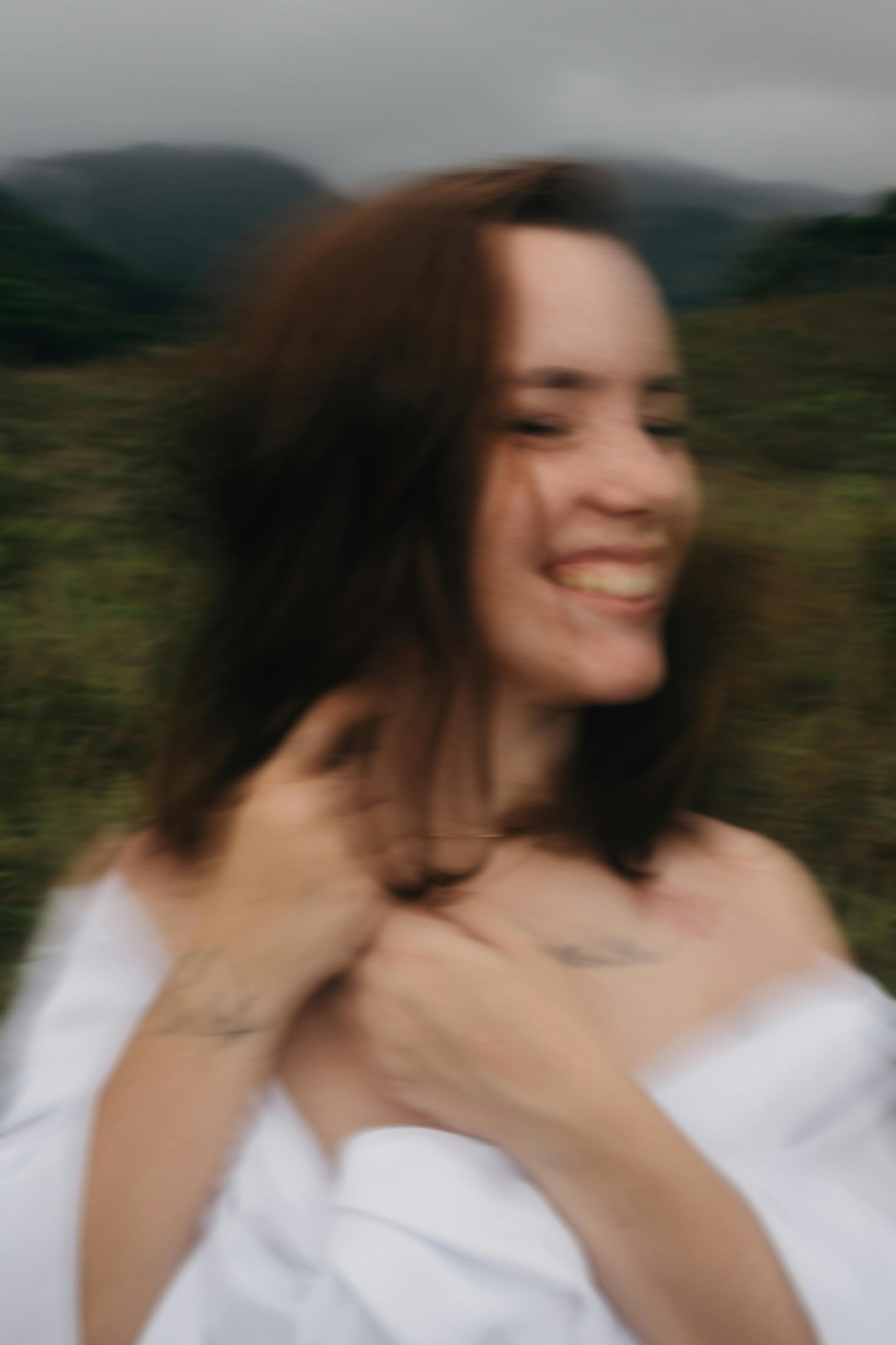 Artistic blurred portrait of a smiling woman outdoors, evoking a sense of joy.
