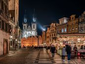 Vibrant night scene of Prague's Old Town Square with Týn Church illuminated.