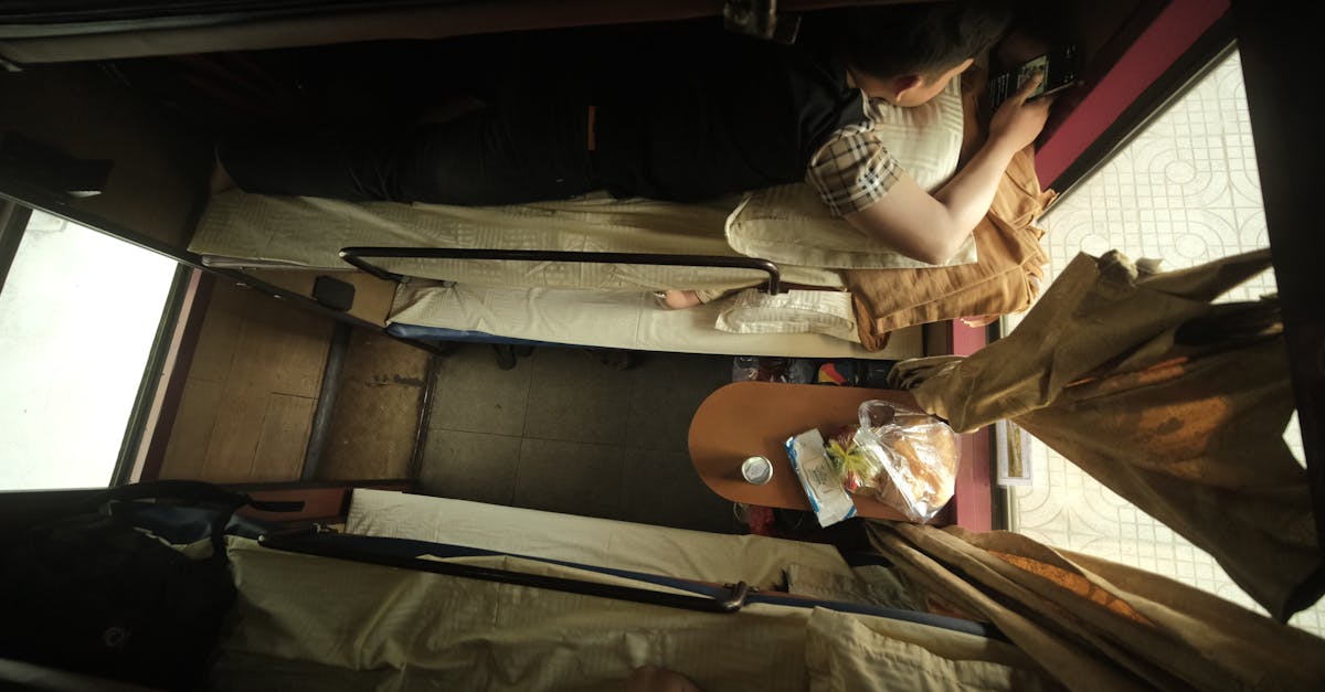 Top view of individuals resting on train bunks with travel essentials.