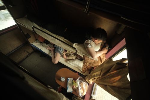 Modern sleeper train cabin with bunk beds and privacy curtains.