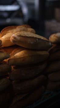 Warmly lit stack of freshly baked bread loaves at a bakery, showcasing rustic artisanal quality.