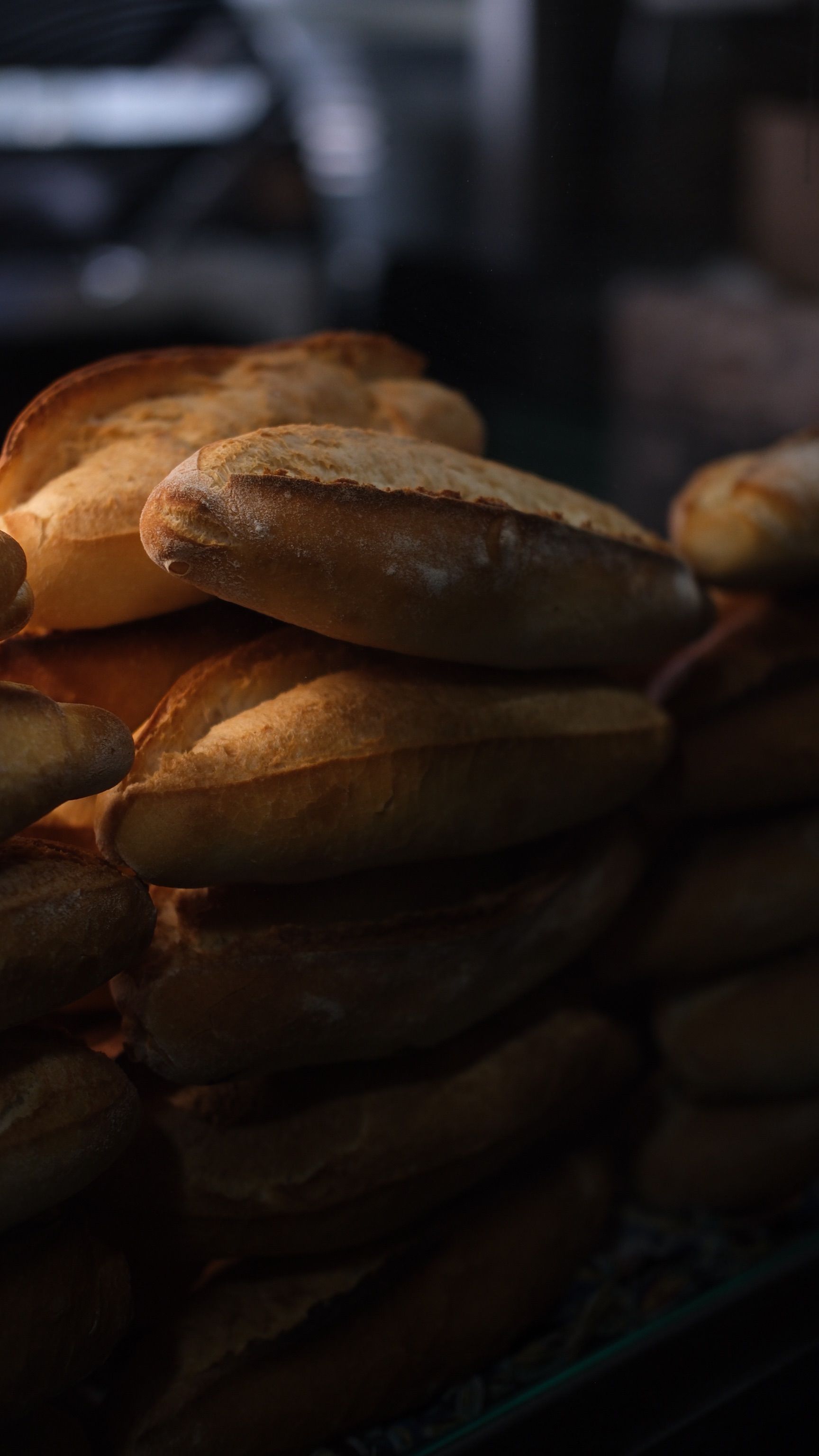 Warmly lit stack of freshly baked bread loaves at a bakery