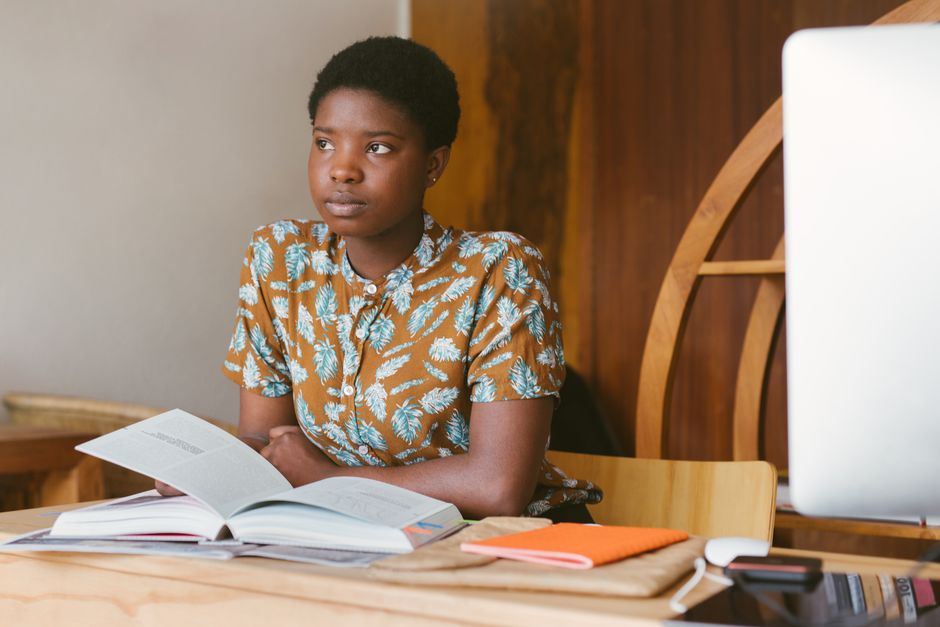 A young woman reading in a peaceful, stylish indoor setting, representing study and learning.
