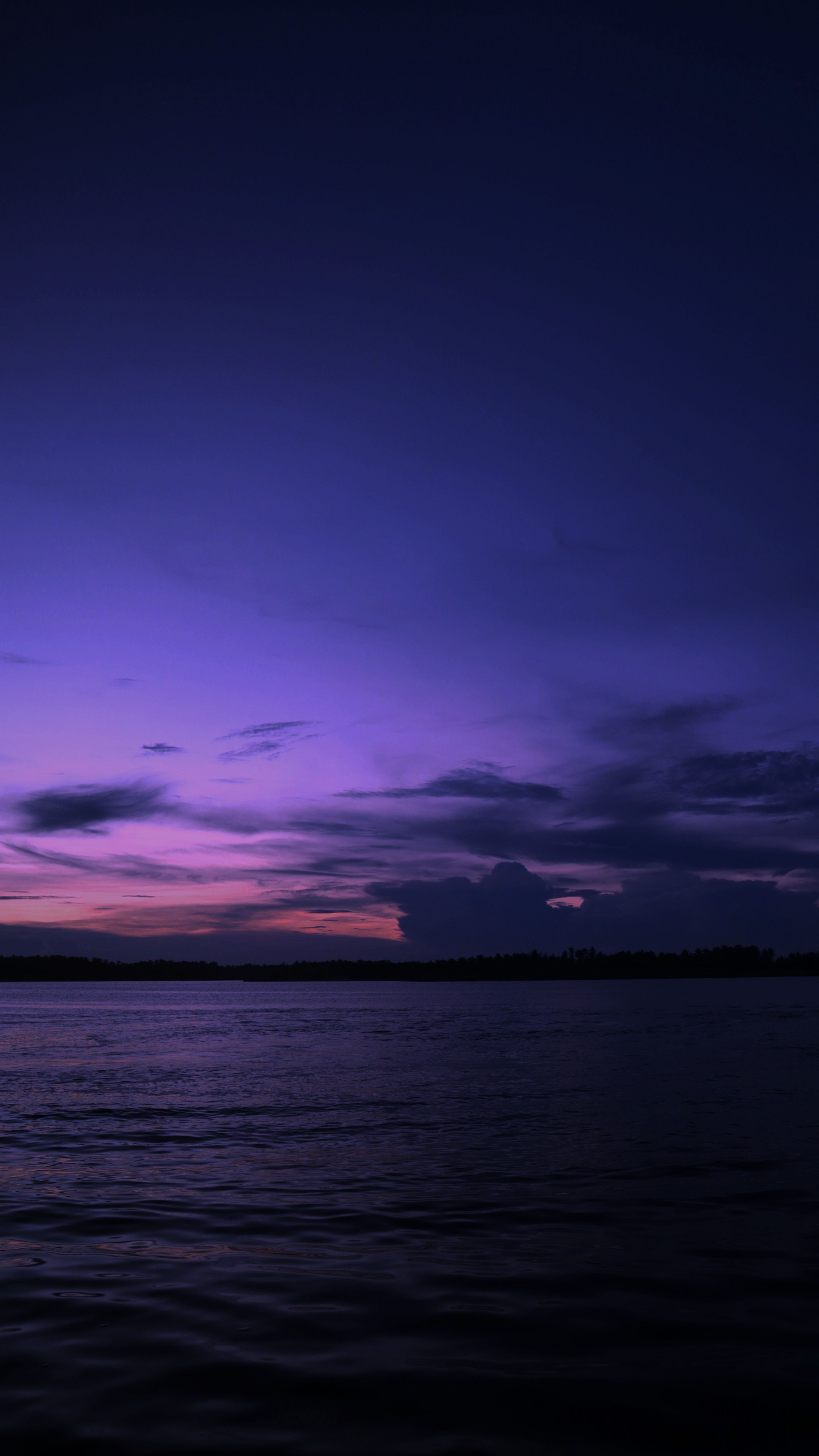 Capture of a serene ocean at twilight with vibrant purple hues and silhouetted horizon.
