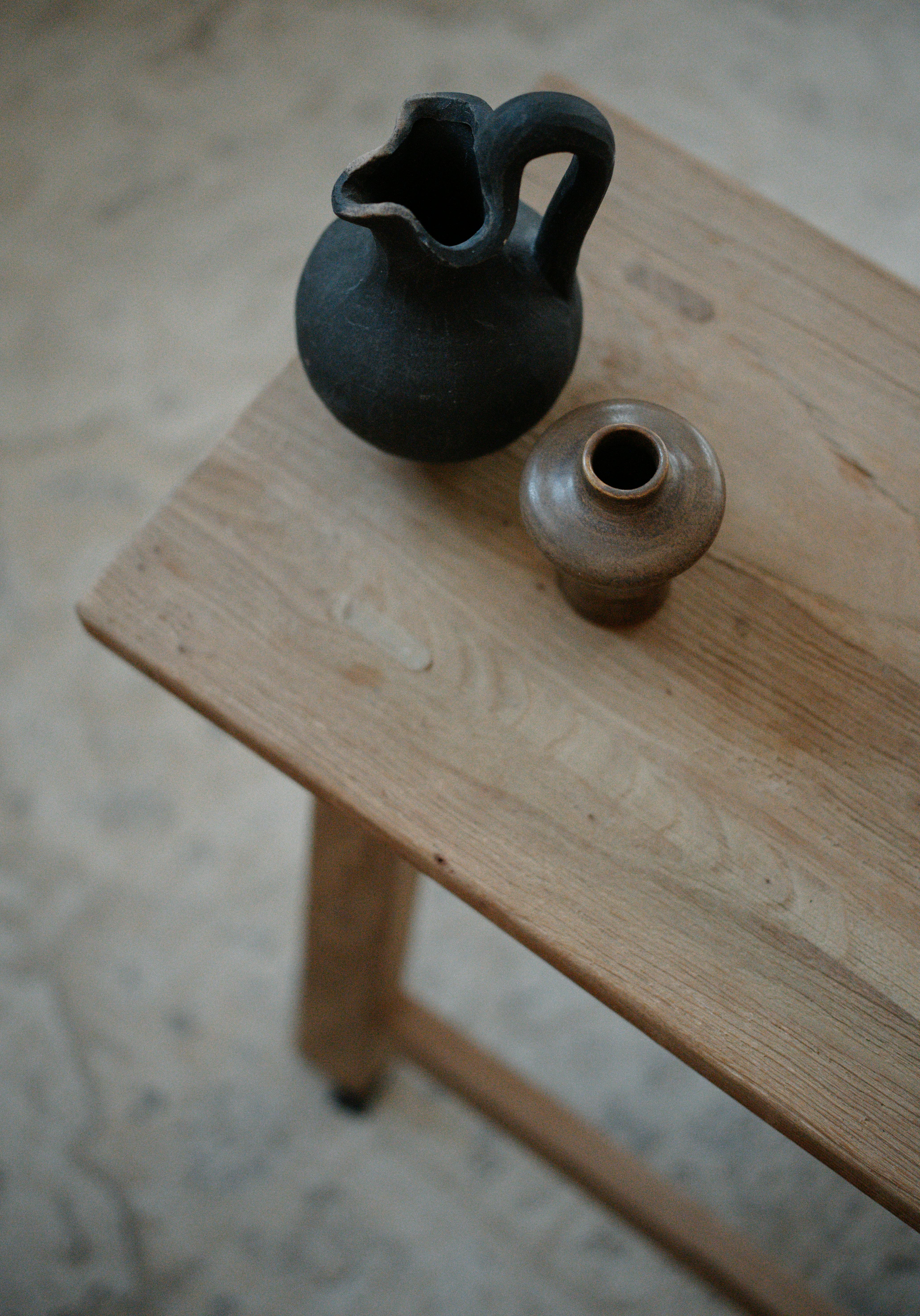 Two minimalist ceramic vases on a rustic wooden table, embracing wabi-sabi style.