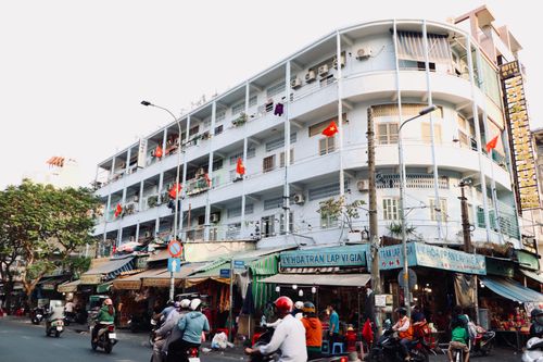 Free Bustling street market under a historic building with Vietnamese flags. Stock Photo