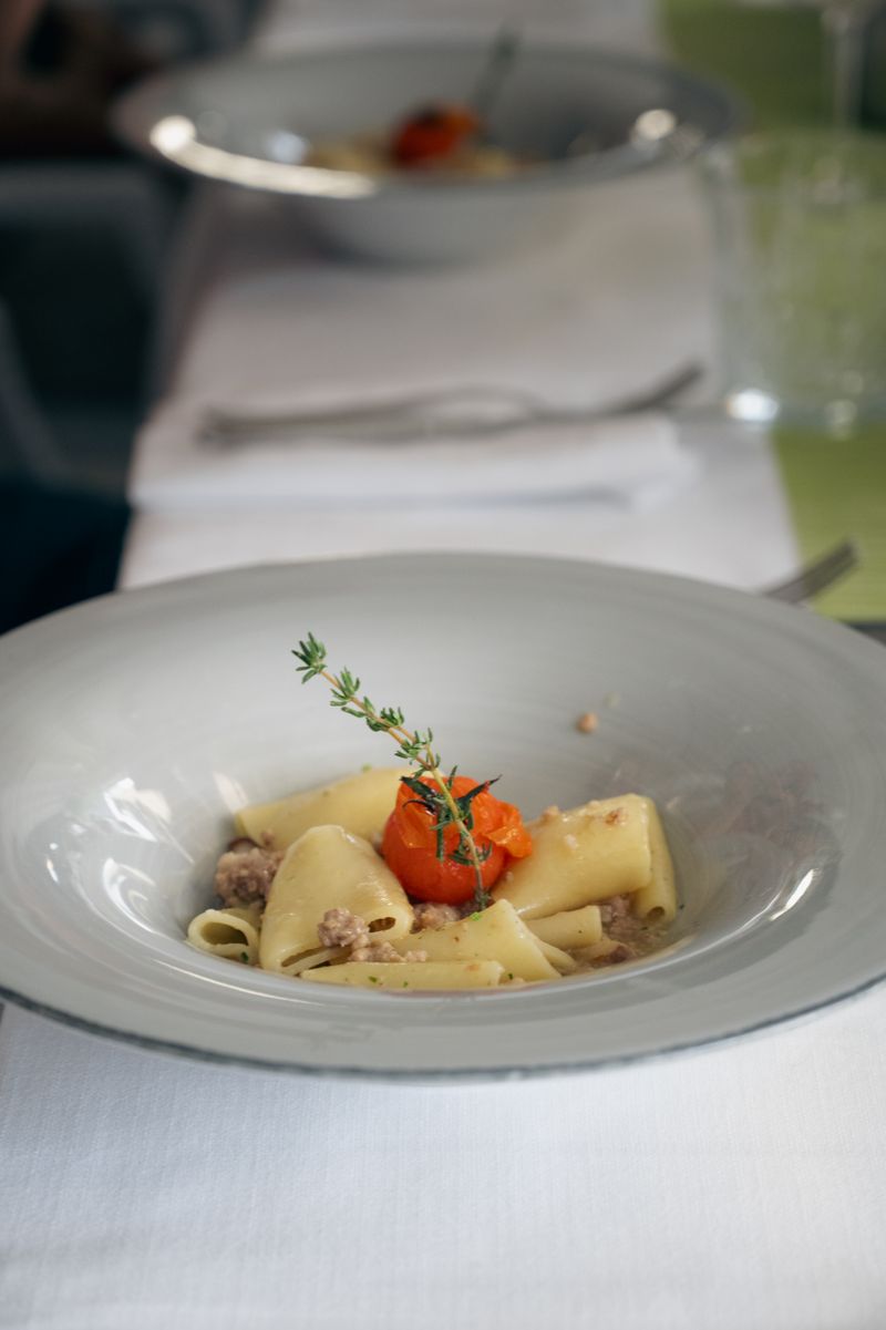 Teller mit Paccheri-Pasta, Ragù und einer geschmorten Tomate