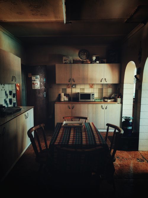 Free Warm, vintage-style kitchen interior with wooden cabinetry and plaid tablecloth. Stock Photo
