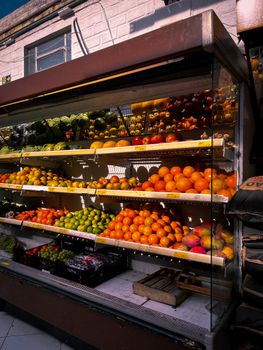 A colorful fruit stand in Campo Bom, Brazil showcasing fresh oranges, apples, and mangoes.