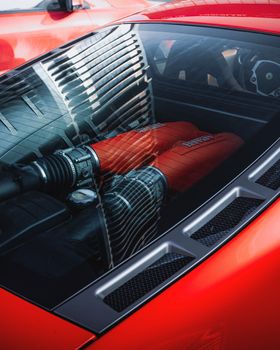 Detailed view of a red sports car engine under a clear cover, reflecting modern design.