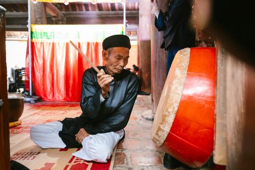 Free Elderly man in traditional attire playing a drum at a cultural ceremony indoors. Stock Photo