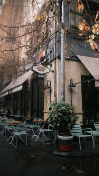 A charming outdoor cafe on a quiet street corner with empty seating and autumn leaves.