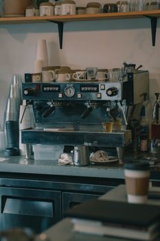 Espresso machine in a cozy cafe with various cups and coffee supplies.