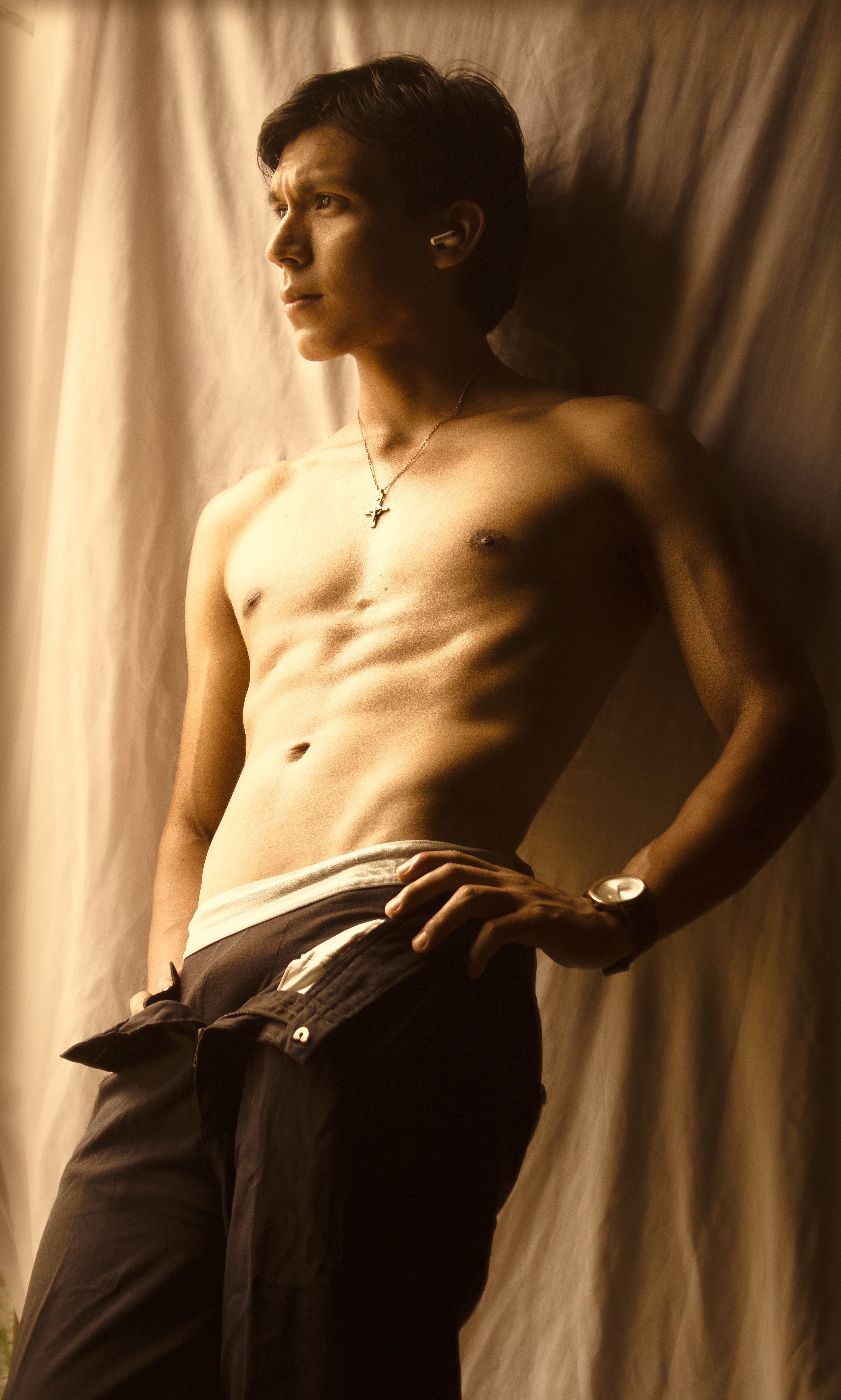 Athletic male model posing against a draped backdrop in sepia tone lighting.