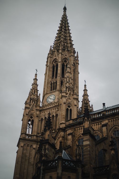 Free Photo of a Gothic-style cathedral featuring an ornate clock tower against a cloudy sky. Stock Photo