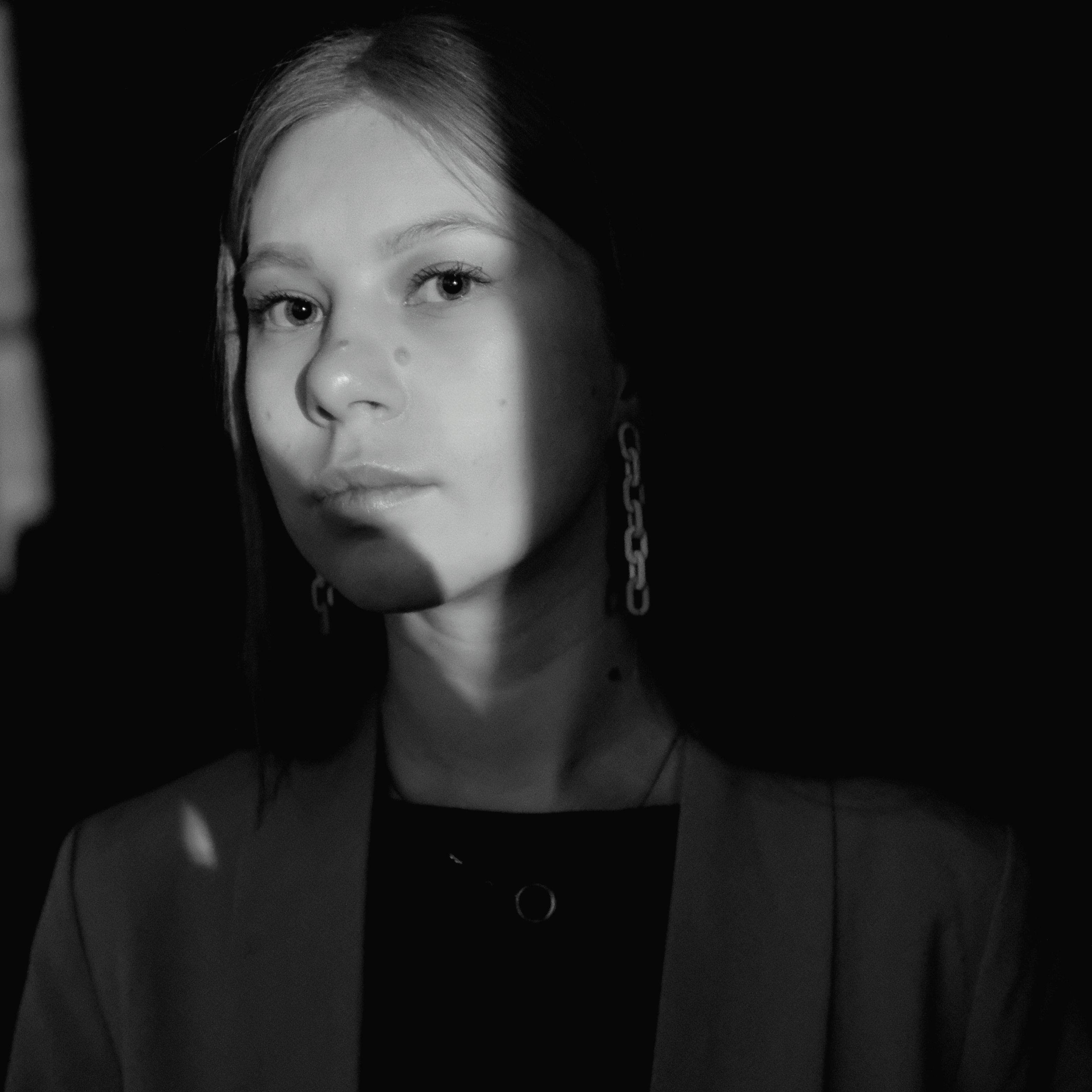 A dramatic black and white portrait of a young woman with shadow play.