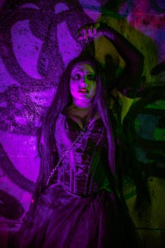 Artistic portrait of a woman in dramatic makeup with vibrant lighting against graffiti.