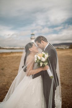 Bride and groom sharing a tender moment outdoors by the lighthouse.