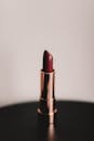 中性背景下，金色管紫红色口红特写，散发着优雅