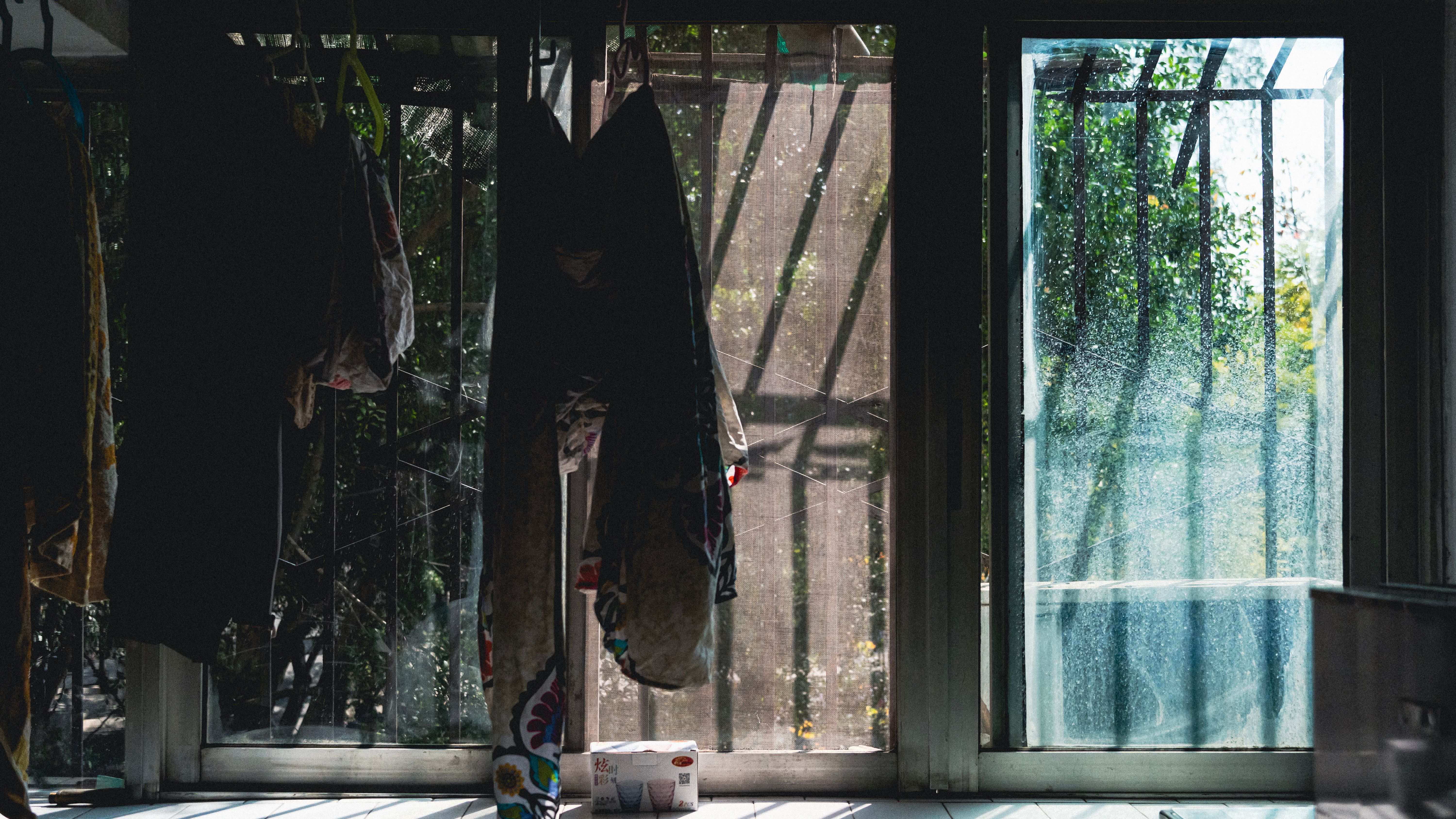Sunlight casts shadows on hanging drapes, creating a moody indoor atmosphere.