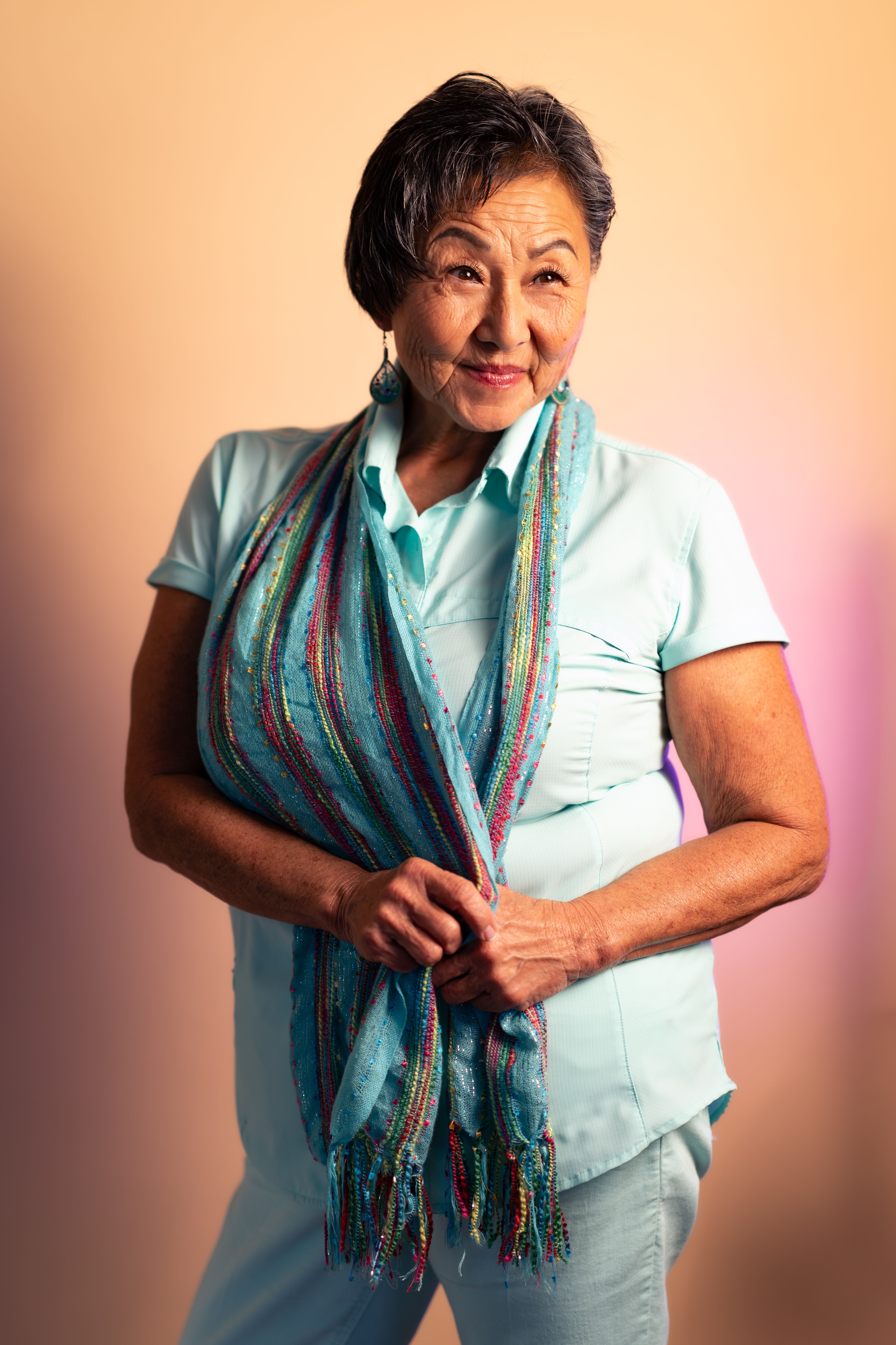 Portrait of a sophisticated senior woman in a colorful scarf and blue attire, smiling warmly.