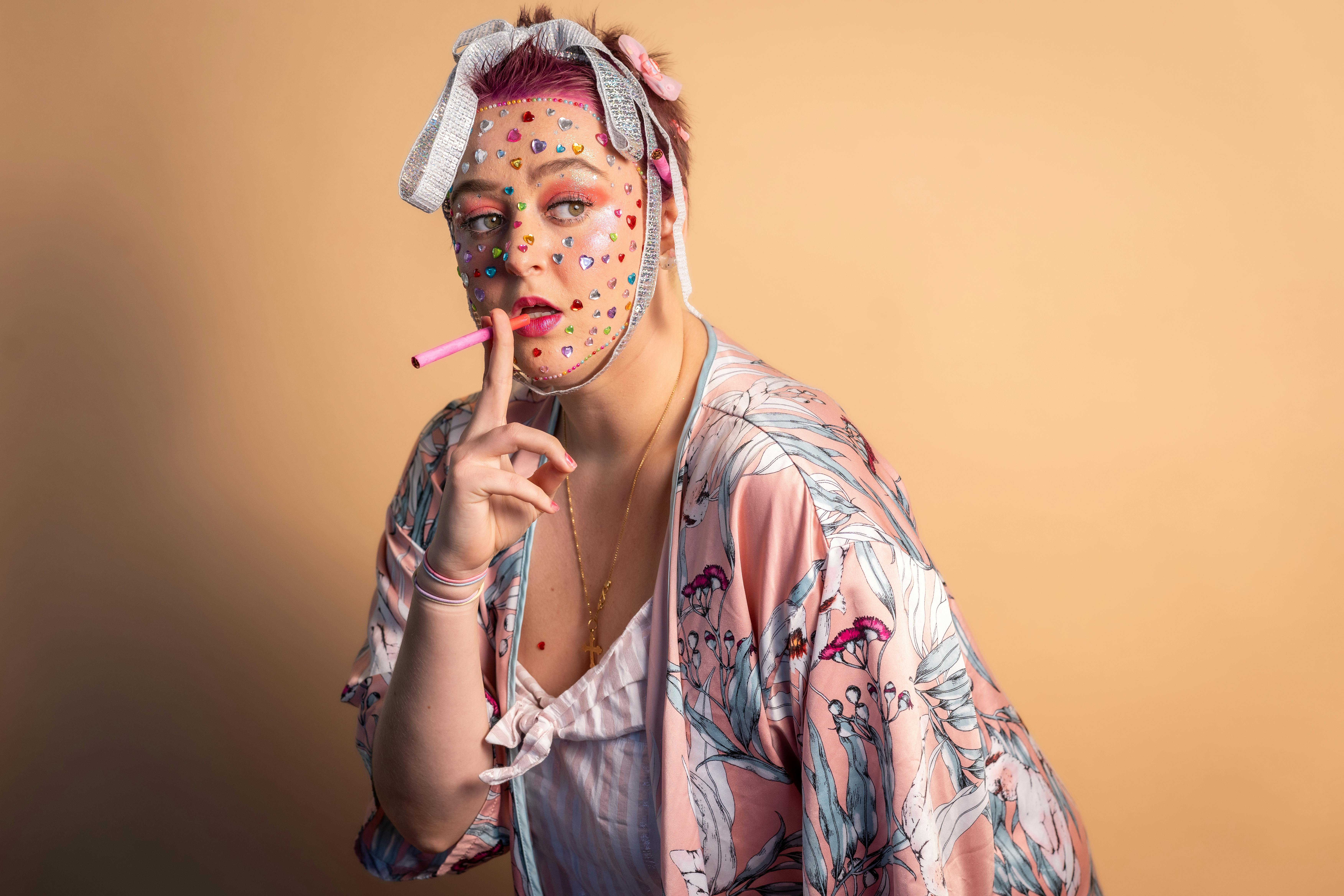 A unique portrait featuring an individual with face stickers and a pink vape, showcasing creative expression.
