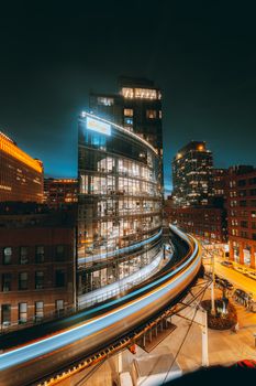 Dynamic night cityscape with bright skyscraper and motion light trails in urban environment.