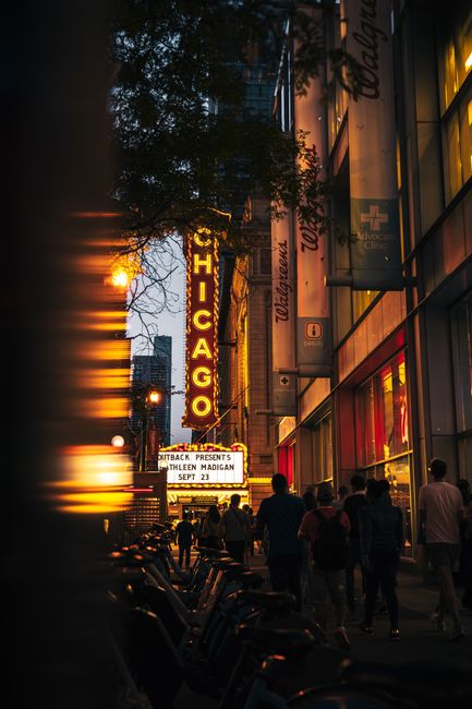 Dusk view of Chicago's lively streets with iconic theater signage and bustling pedestrians.