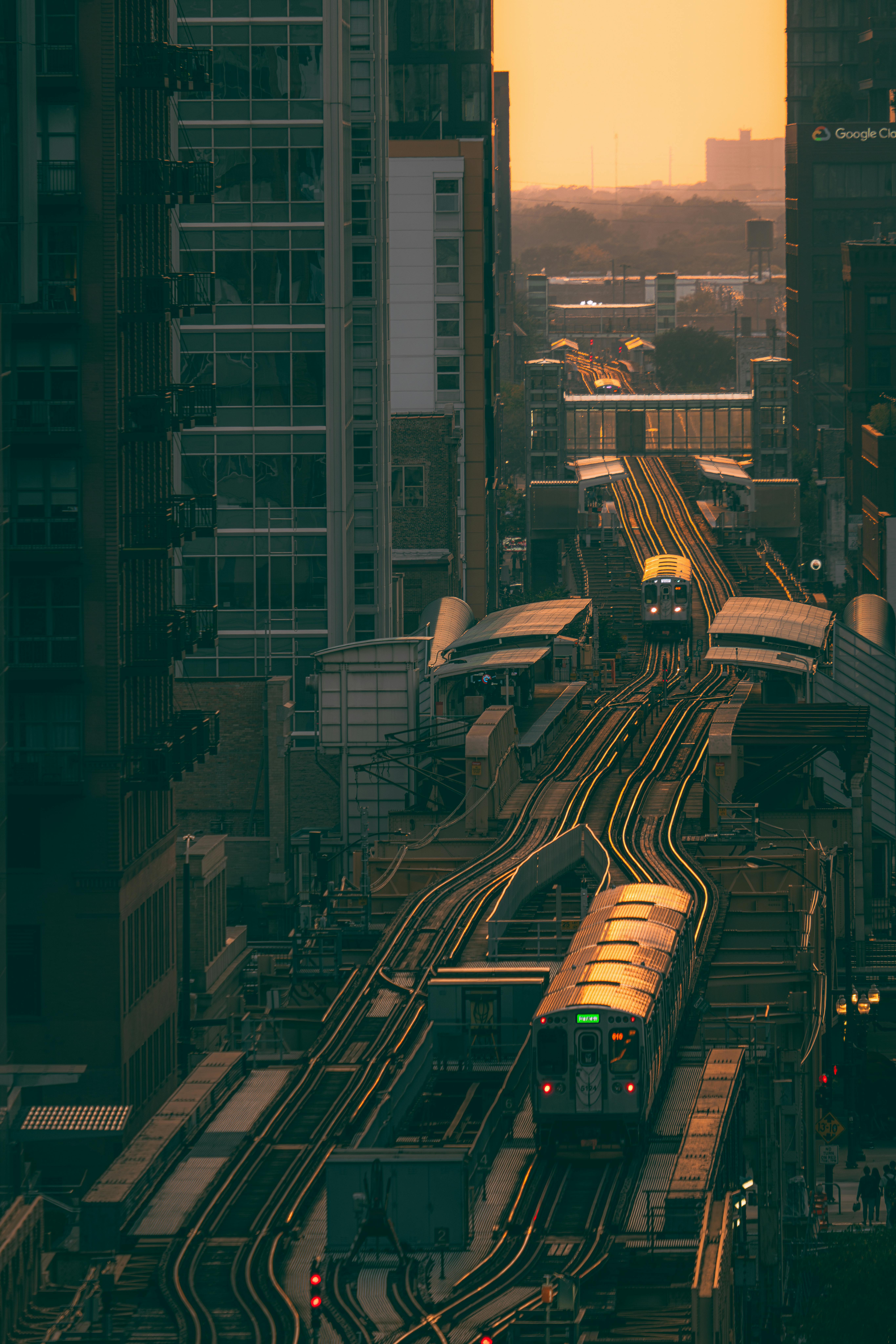 Aerial view of trains navigating city tracks at sunset, creating a dynamic urban atmosphere.