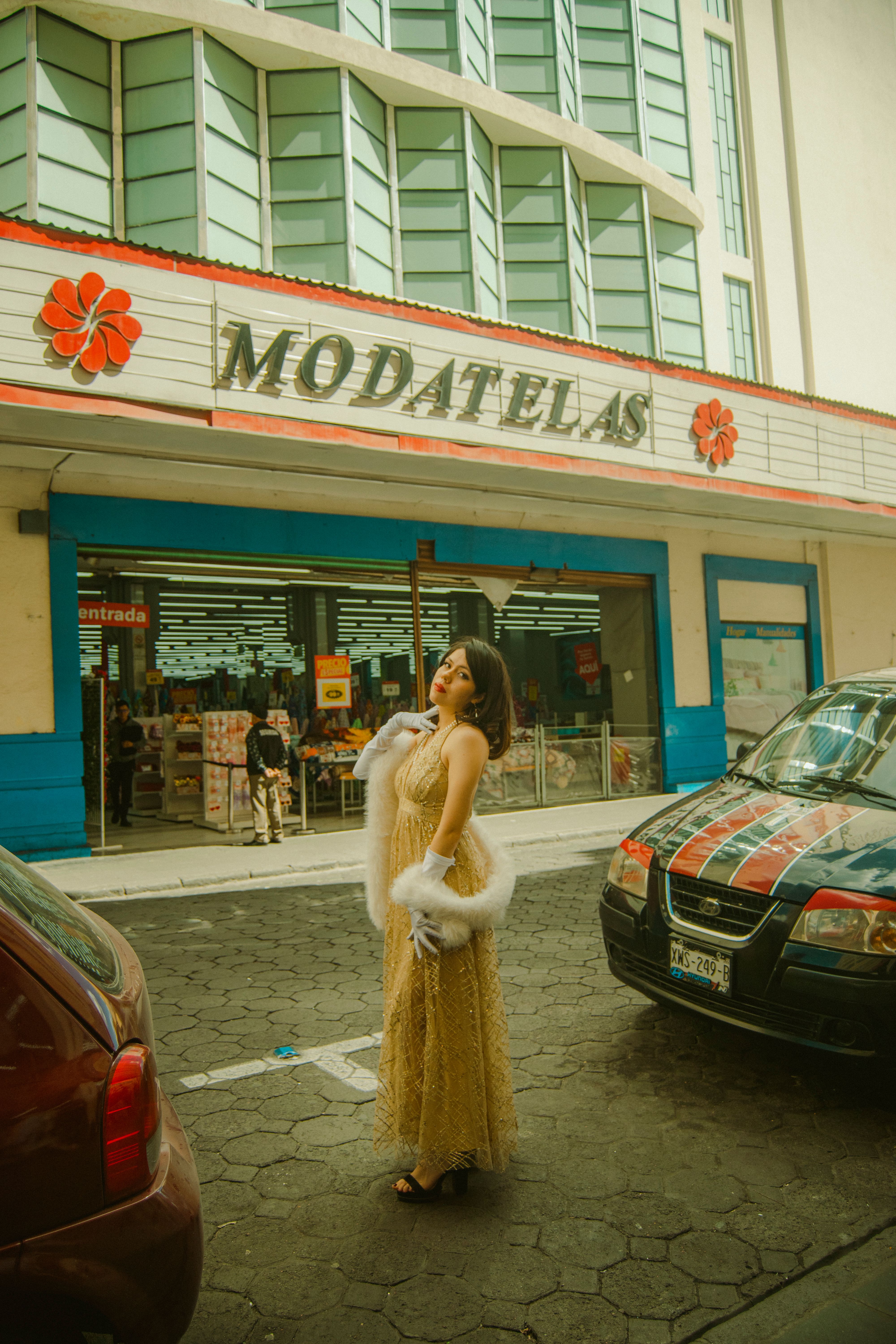 Elegant woman in a vintage dress posing outside a storefront, creating a retro ambiance.