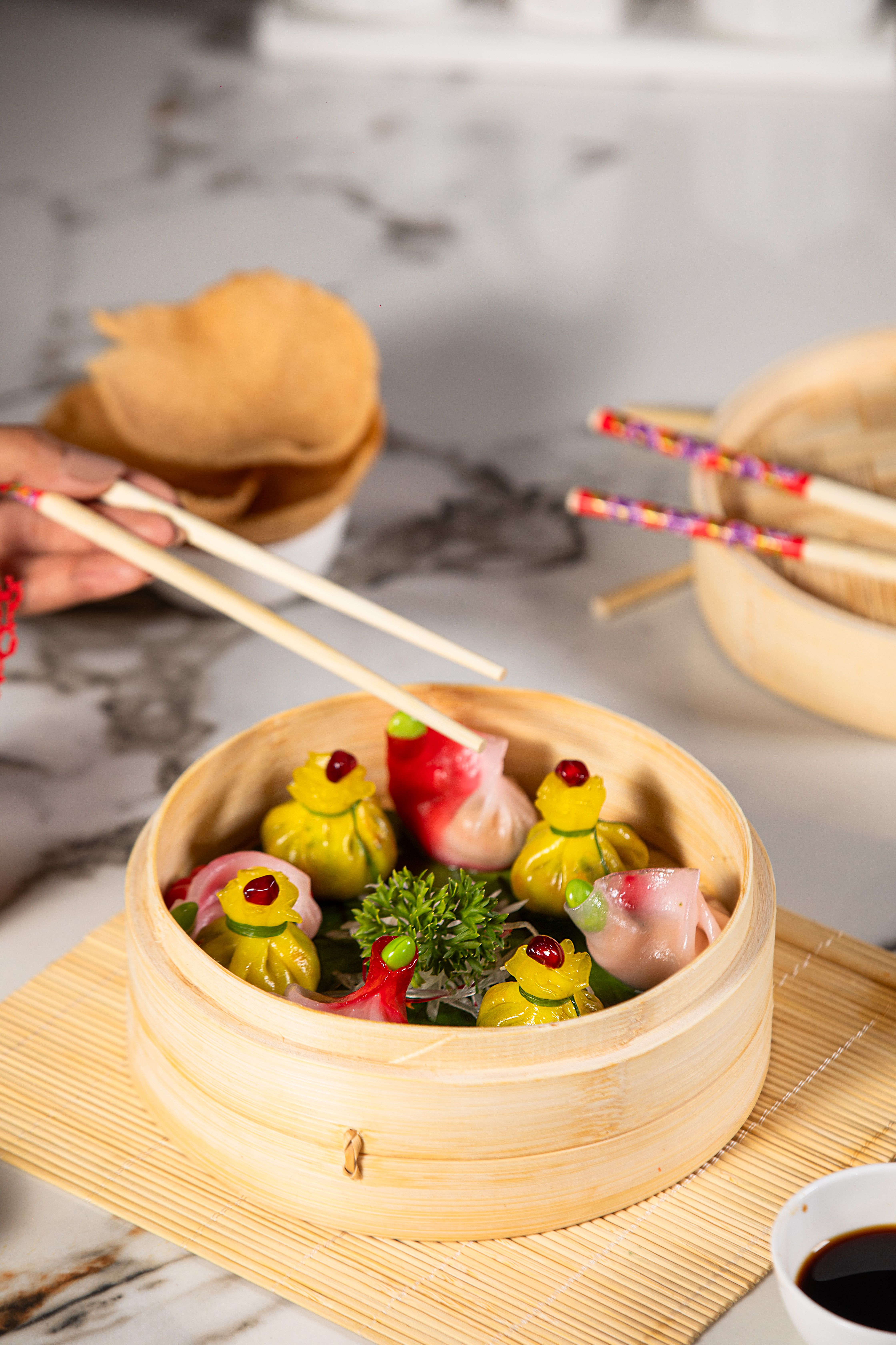 Colorful dumplings served in a bamboo steamer, accompanied by chopsticks, offering a taste of Asian cuisine.