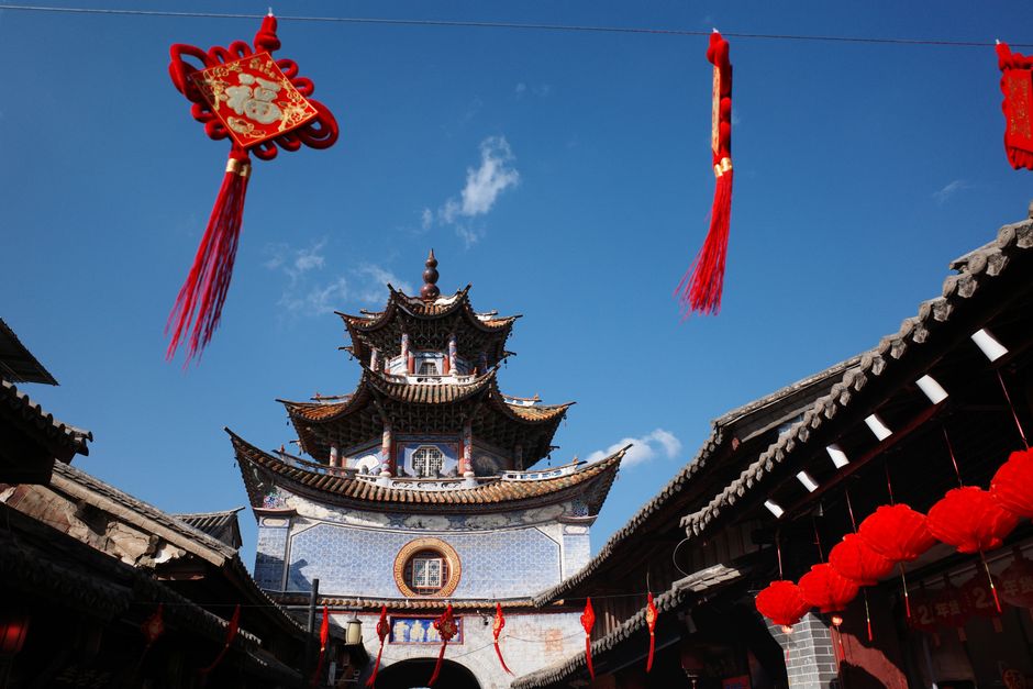 Chinese pagoda and red lanterns under a vibrant blue sky, celebrating traditional architecture and culture.