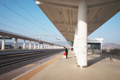 Free Traveler waits at a modern train station under a bright blue sky. Stock Photo