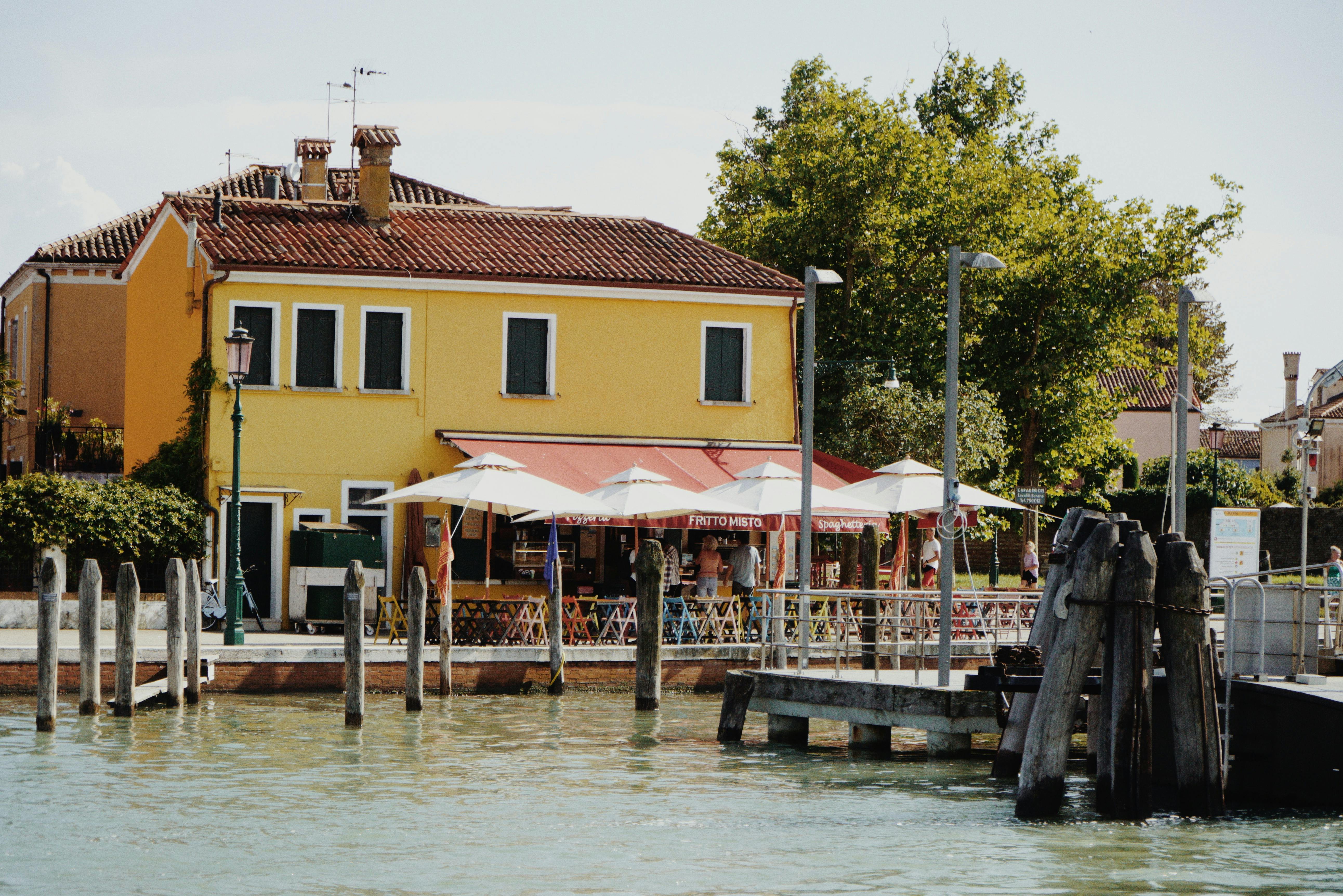 Colorful waterfront building with cafe in Burano, Venice, Italy under summer sun.