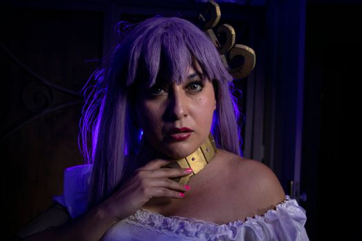 A woman in a fantasy-themed cosplay with purple hair and dramatic lighting.