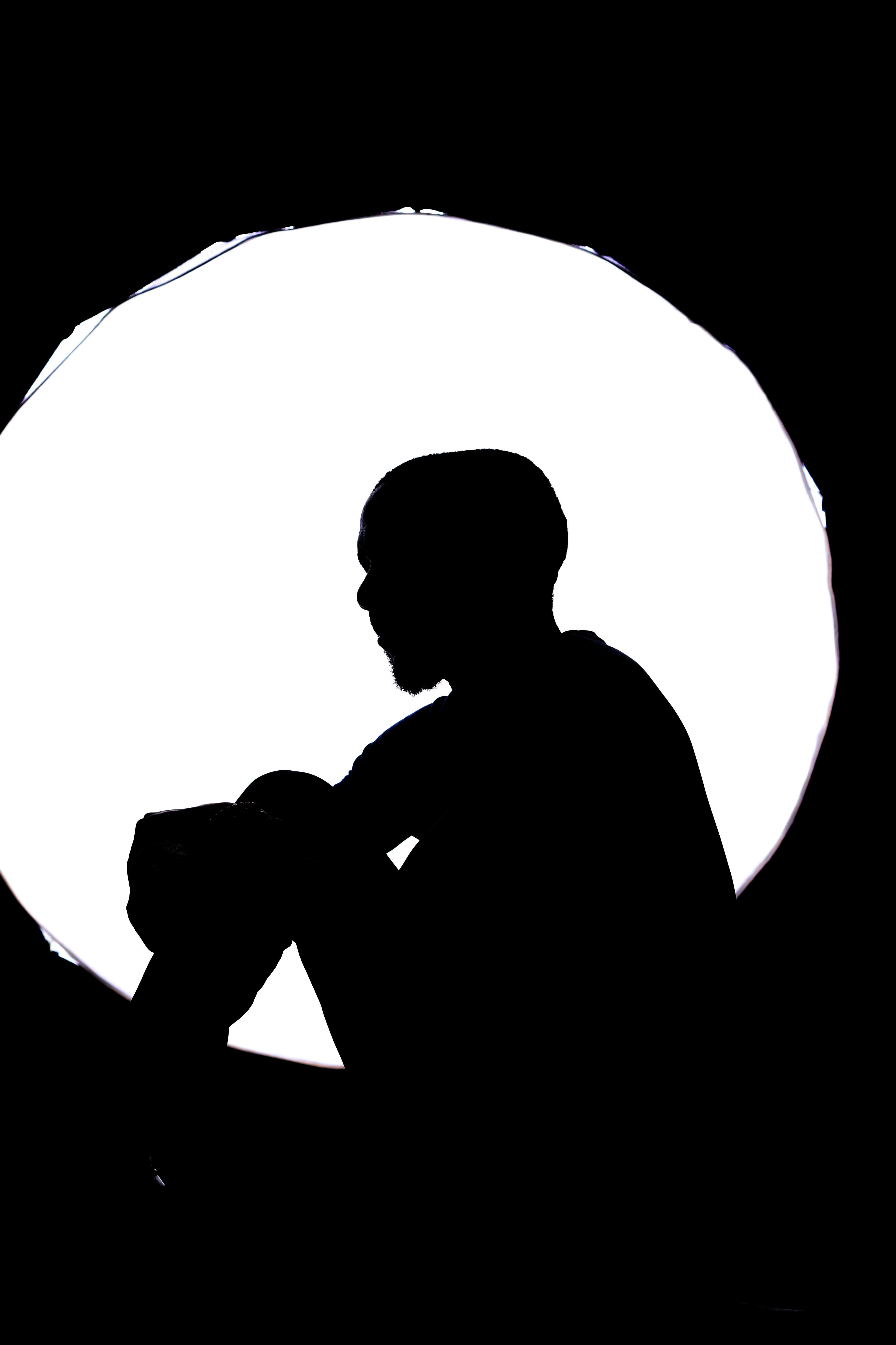 Gratis Silhouette spettacolare di una persona seduta su uno sfondo circolare luminoso. Foto a disposizione