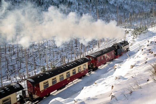 A classic steam locomotive travels through a snowy winter landscape near Wernigerode, Germany.
