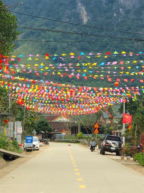 Festive street with vibrant flags in rural Quảng Bình, Vietnam, creating a cheerful atmosphere.